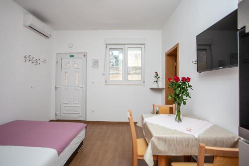 una habitación con 2 camas y una mesa con flores. en AP PUNTA next to sandy beach, apartment with garden, en Omiš