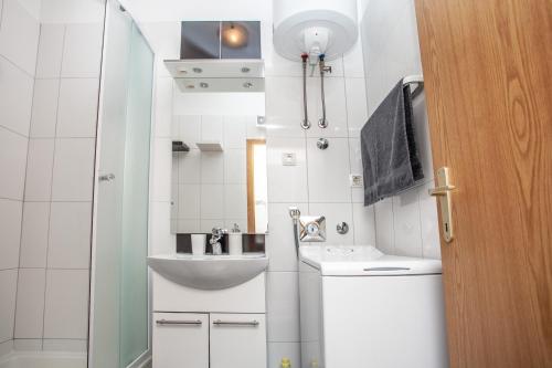 Un baño pequeño con lavabo y espejo. en AP PUNTA next to sandy beach, apartment with garden, en Omiš