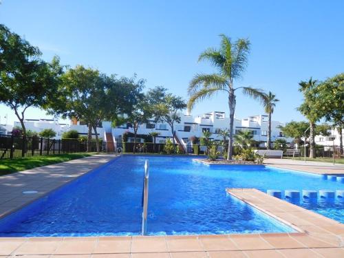 una piscina azul con palmeras y edificios en Condado de Alhama, en Alhama de Murcia