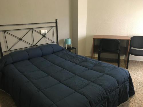 1 dormitorio con 1 cama azul, escritorio y mesa en Hostal San Miguel, en León