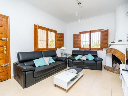 a living room with a black leather couch and a fireplace at Villa Aurelie by Interhome in Balcon del Mar