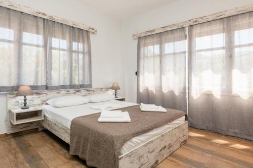 a bedroom with two beds and large windows at Ioanna Studios in Skala Kallirakhis