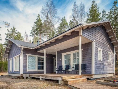 a house with a porch and chairs on a deck at Holiday Home Koholahti by Interhome in Jäniskylä