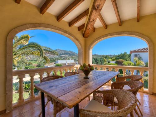 een eetkamer met een houten tafel en stoelen op een balkon bij Villa Meena by Interhome in Benitachell