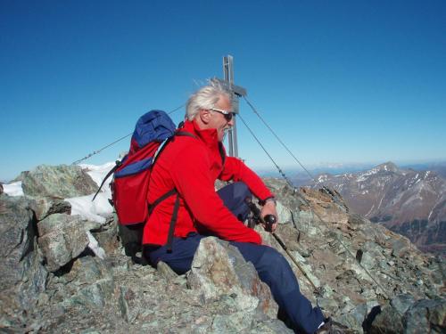 a man with a backpack sitting on the top of a mountain at Pension Trojerhof in Heiligenblut
