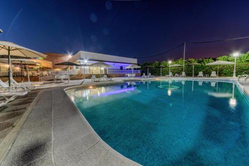 a large swimming pool at night with chairs and umbrellas at Hotel Torre De Los Guzmanes in La Algaba