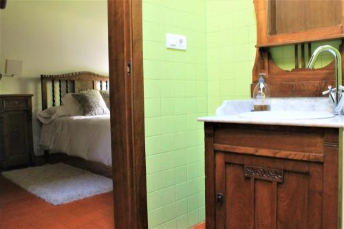 a bathroom with a sink and a bedroom with a bed at casa da pedra in Tomiño