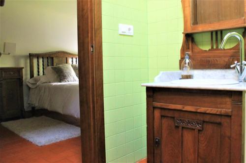 łazienka z umywalką oraz sypialnia z łóżkiem w obiekcie casa da pedra w mieście Tomiño