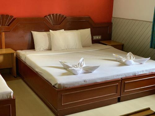 a bed with two white flowers on it at JC Woodville Manor in Kodaikānāl