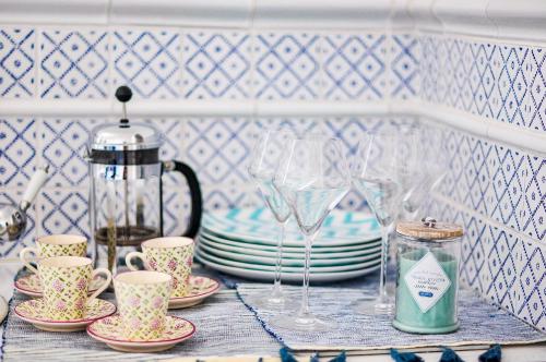 une étagère avec des assiettes, des verres et une théière dans l'établissement Vue Mer Côte de Granit Rose en Bretagne, à Trébeurden