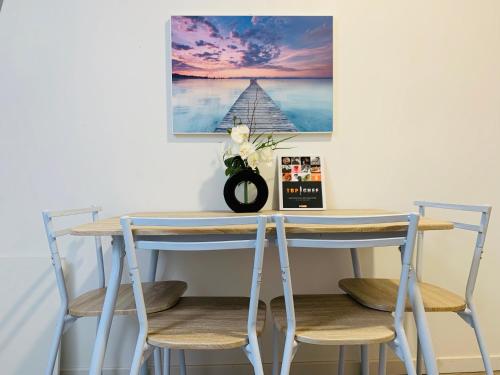 een tafel met drie stoelen en een foto aan de muur bij Le MonMon grand T2 hyper centre ville in Fontenay-le-Comte