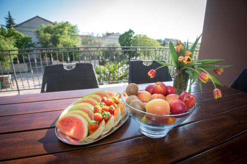 a wooden table with two bowls of fruit and a bowl of watermelon at Lucija in Starigrad-Paklenica