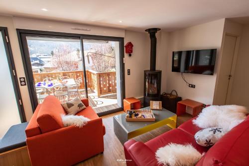 a living room with two red couches and a fireplace at Chalet Hygge Saint Lary - gîtes de standing en coeur de village des Pyrénées in Saint-Lary-Soulan