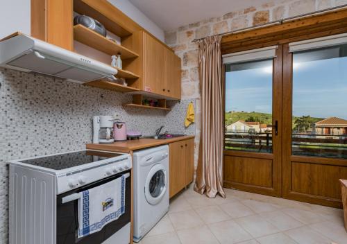 a kitchen with a washing machine and a window at Villa windmill Near Shipwreck Beach in Volimes