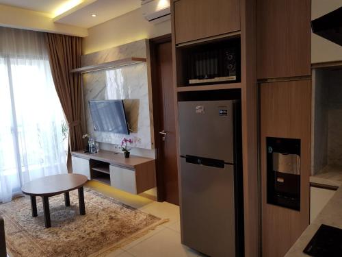 cocina con nevera, mesa y escritorio en M-Town Signature Gading Serpong by J`s Luxury Apartment en Pumpangsineng