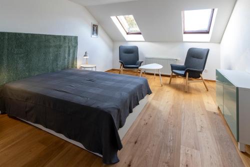 a bedroom with a bed and two chairs and a table at Flataid Apartmenthaus Brauhausstrasse in Graz