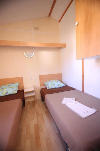 a small room with two beds in a room at Camping Le Ruisseau in Saint-André-de-Seignanx
