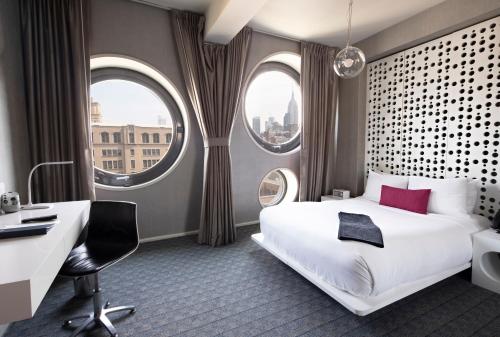 um quarto de hotel com uma cama, uma secretária e duas janelas em Dream Downtown, by Hyatt em Nova York