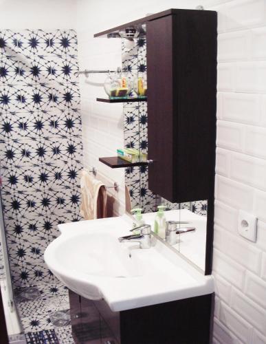 a bathroom with a white sink and a black and white tiles at Campo de Oleandros in Lourinhã