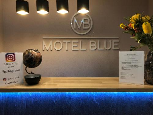 a counter with a model blue sign and flowers on it at Motel Blue in Berlin