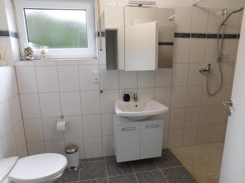 a white bathroom with a toilet and a sink at Ferienwohnung Elsbeere in Blankenheim