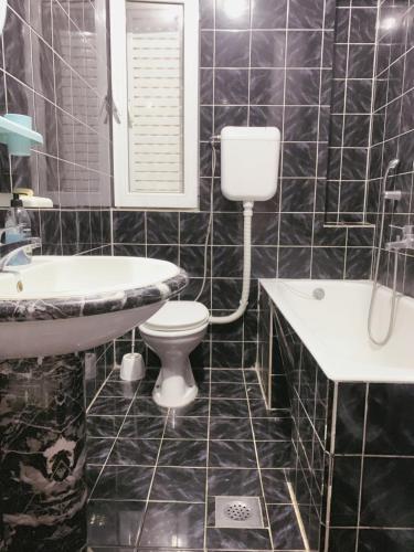 a black tiled bathroom with a toilet and a sink at Hostel Holiday Cetinje in Cetinje