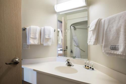 a bathroom with a sink and a mirror and towels at Red Lion Inn & Suites Butte in Butte