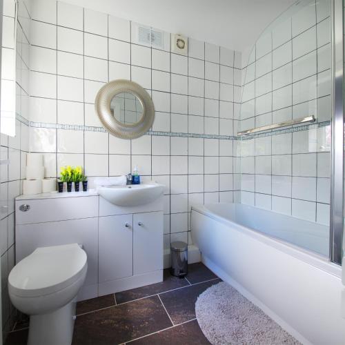 a bathroom with a tub and a toilet and a sink at Stylish and Comfortable Home Away From Home in Liverpool