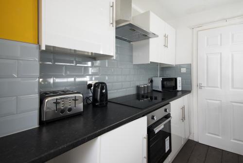 a kitchen with white cabinets and a black counter top at Stylish and Comfortable Home Away From Home in Liverpool