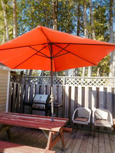 an orange umbrella sitting on a deck with a grill at Rothesay Motel in Rothesay