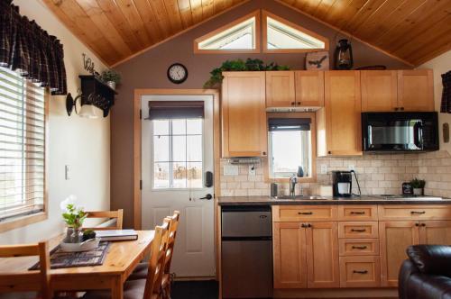 a kitchen with wooden cabinets and a table with a dining room at Prairie Rose Cottage in Fort Macleod