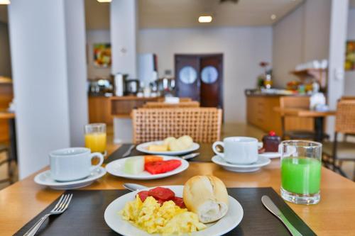 a table with plates of breakfast food on it at Comfort Hotel Joinville in Joinville
