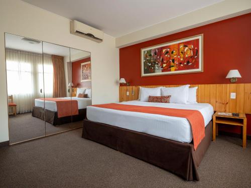 una camera d'albergo con un grande letto e uno specchio di Qorianka Hotel a Lima