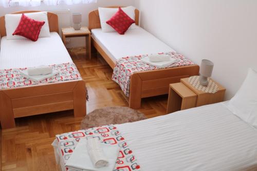 une chambre avec trois lits avec des oreillers rouges dans l'établissement Apartman DORA, à Trebinje