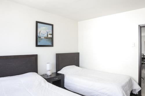 a bedroom with two beds and a picture on the wall at Departamento Completo Frente Al Mar San Lorenzo Salinas in Salinas