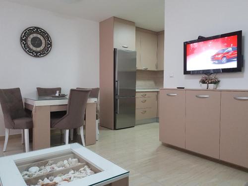 eine Küche mit einem Tisch und einem TV an der Wand in der Unterkunft Apartman KRISTINA,Istocno Sarajevo,Vojvode Radomira Putnika 49D in Sarajevo
