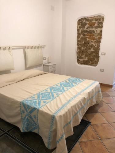 1 dormitorio con cama y pared de piedra en Casa della Nonna, en San Giovanni Suergiu