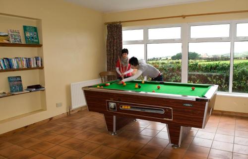 two people playing pool in a room with a pool table at Giant's Causeway Holiday Cottages in Bushmills