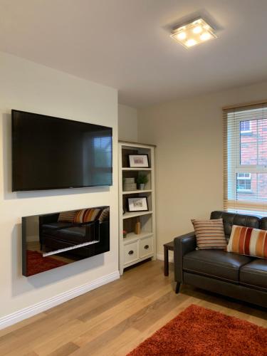 a living room with a black couch and a flat screen tv at 4 bed Duplex Apartment, Belfast in Belfast