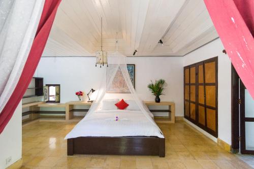 a bedroom with a bed with a mosquito net at Puri Angsa Saba in Keramas
