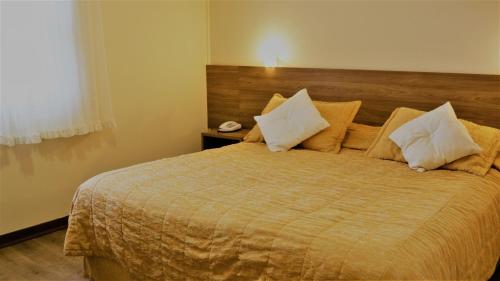 a bedroom with a large bed with white pillows at Hotel Bologna in Campos do Jordão