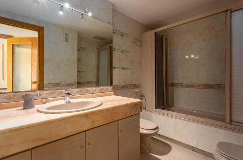 een badkamer met een wastafel, een toilet en een spiegel bij apartament de luxe con piscina in Salou