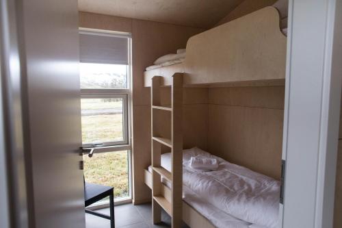 a small bedroom with bunk beds and a window at Einishus Cottages in Laugar