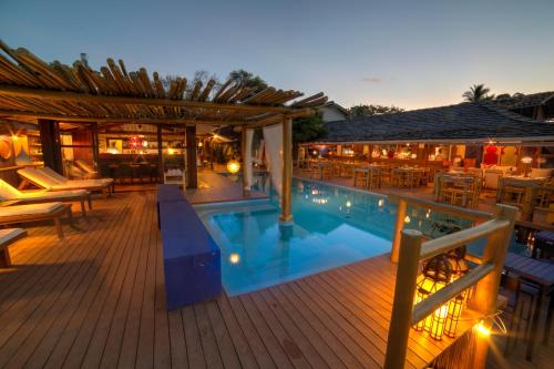 a pool with tables and chairs on a wooden deck at Pousada El Gordo in Trancoso