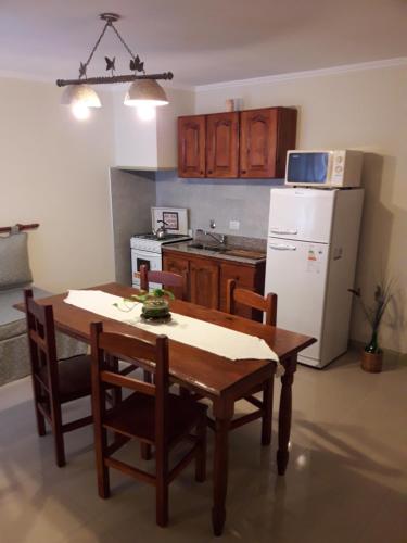 a kitchen with a wooden table and a white refrigerator at Depto en La Vicente! in Olavarría
