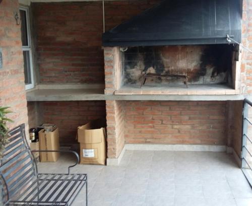 a brick patio with a fireplace and a bench at La Palmera escondida in Colón