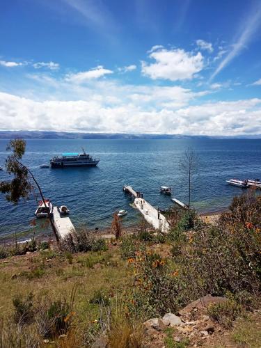 a large ship in the water with boats on the shore at Hostal Qhana Pacha in Isla de la Luna