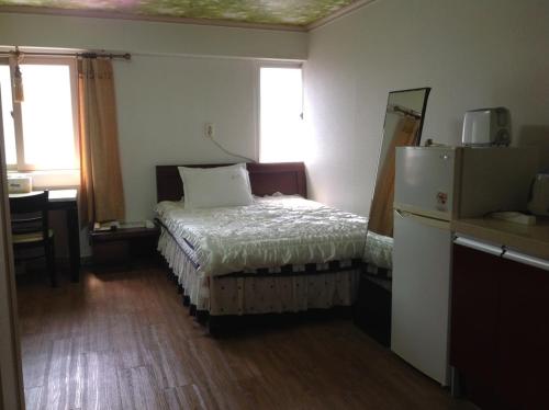 a bedroom with a bed and a desk and window at Hi Hotel in Ulsan