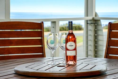 una botella de vino y dos copas de vino en una mesa en Bayside - Aldinga Beach - C21 SouthCoast Holidays en Aldinga Beach