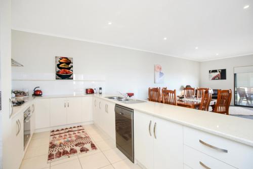 Una cocina con gabinetes blancos y una mesa y sillas. en Bayside - Aldinga Beach - C21 SouthCoast Holidays, en Aldinga Beach